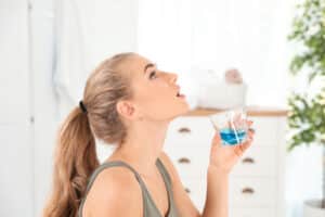 Woman rinsing mouth with mouthwash in bathroom